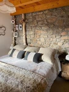 a bedroom with a stone wall and a bed with pillows at Idílico refugio de montaña ideal escapadas in Olopte