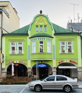 een geel en groen gebouw met een auto voor de deur bij Ubytování u Tranů in Vrchlabí