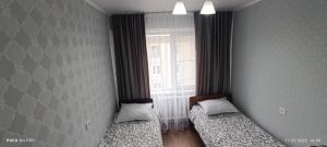 zwei Betten in einem Zimmer mit Fenster in der Unterkunft Lux Home на Новаторов in Öskemen