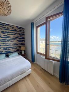 um quarto com uma cama e uma grande janela em Appartement 3p 70m2, vue mer, plage et port de Lomener em Ploemeur