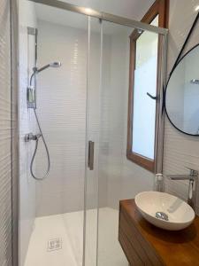 uma casa de banho com uma cabina de duche em vidro e um lavatório. em Appartement 3p 70m2, vue mer, plage et port de Lomener em Ploemeur