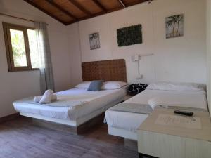 1 dormitorio con 2 camas, mesa y ventana en Finca Hotel La Estancia, en Santa Fe de Antioquia