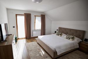 a white bedroom with a bed and a television at Comfy House in Borşa