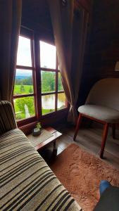 a bedroom with a bed and a window and a chair at Recanto Pôr do Sol in Nova Petrópolis