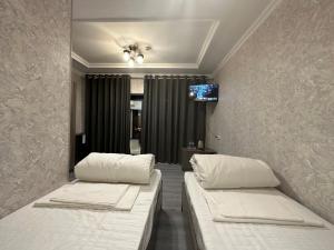 タシュケントにあるByond Hotel & Hostelのベッド2台、壁掛けテレビが備わる客室です。