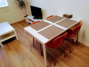 a white table with red chairs in a room at Apartman Coral in Prague