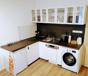 a small kitchen with white cabinets and a washing machine at Apartman Coral in Prague