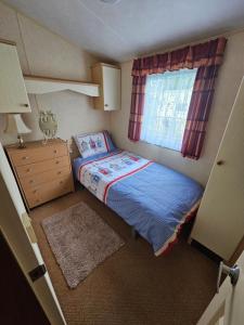 ein kleines Schlafzimmer mit einem Bett und einem Fenster in der Unterkunft Liberty Caravan Hire in Chapel Saint Leonards