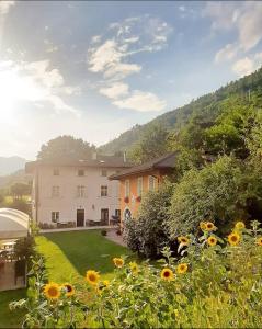 een groot huis met een tuin met zonnebloemen bij Agritur Cantina Romanese in Levico Terme
