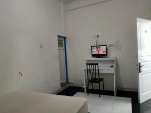 Zimmer mit Schreibtisch und TV in der Unterkunft OYO 93122 Pondok Puti Sartika Syariah in Banjarmasin