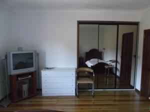 ein Wohnzimmer mit einem TV und einer Kommode mit einem Stuhl in der Unterkunft Albergue Constantino AL in Paredes de Coura