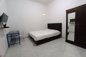 een slaapkamer met een bed, een tafel en een spiegel bij OYO 93126 Nrc White House in Duri