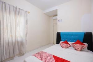 - une chambre avec un lit doté d'oreillers rouges et blancs dans l'établissement OYO 93130 Baloi Homestay, à Nagoya