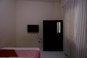 - une chambre avec un lit et une télévision murale dans l'établissement OYO 93130 Baloi Homestay, à Nagoya