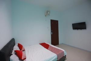 een slaapkamer met een bed met rode kussens en een flatscreen-tv bij OYO 93131 Mamapapahouse in Batam Center