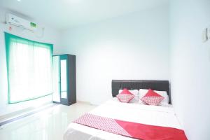 een slaapkamer met een bed met rode en witte kussens bij OYO 93131 Mamapapahouse in Batam Center