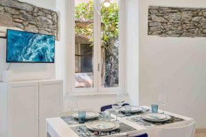 a white kitchen with a table with plates and wine glasses at Il Profumo del Mosto, Terre Marine in Vernazza +4 photos