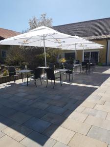 a patio with tables and chairs under an umbrella at Hotel/Pension Rast& Ruh in Zodel