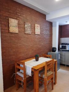 a dining room table with chairs and a brick wall at Temporario Necochea 1 corrientes in Corrientes