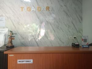 a reception desk with a tico dance sign on a wall at OYO 93117 Penginapan Tiga Dara in Jayapura
