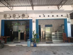 OYO 93117 Penginapan Tiga Dara في جايابورا: واجهة متجر بأبواب زرقاء ونبات الفخار