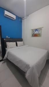 a large white bed in a room with a blue wall at OYO 931O12 Tamara Homestay Syariah in Medan