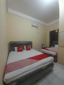 a bedroom with two beds with red pillows on them at OYO 931O12 Tamara Homestay Syariah in Medan