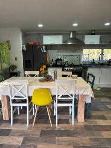 eine Küche mit einem Tisch mit 4 Stühlen und einem gelben Stuhl in der Unterkunft Casa En medio del Bosque in Puerto Varas