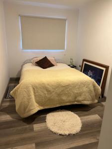 ein Schlafzimmer mit einem Bett mit einer Decke und einem Teppich in der Unterkunft Casa En medio del Bosque in Puerto Varas