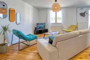 a living room with a couch and chairs and a tv at Le Havre Chic et Spacieux d'Angoulême - Calme & Confort Moderne in Angoulême