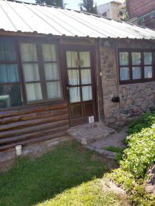 ein Steinhaus mit einer Holztür und Fenstern in der Unterkunft Cabañas Pacari Tampu in Mendoza