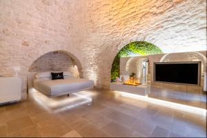 a bedroom with a bed and a tv in a stone wall at La Mandorla Luxury Trullo in Alberobello
