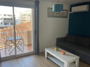 een woonkamer met een bank en een tafel en een balkon bij Superbe studio à Canet en Roussillon proche de la plage in Canet-en-Roussillon