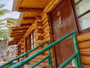 eine Holztür eines Blockhauses mit grünem Geländer in der Unterkunft Cabañas Pacari Tampu in Mendoza