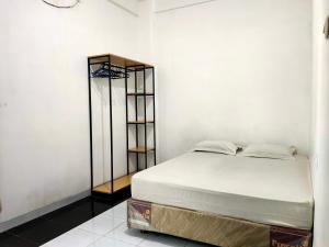 Bett in einem Zimmer mit einer weißen Wand in der Unterkunft OYO 93152 Azwa Gh Katingan 