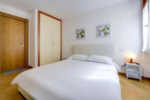 a white bedroom with a large white bed and a door at Appartamenti Anna in Sirmione