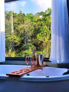 two glasses of wine sitting on a table with a window at Cabana Vale Encantado in São Bento do Sapucaí