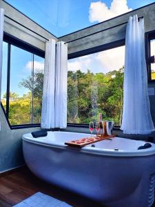 uma banheira na casa de banho com uma grande janela em Cabana Vale Encantado em São Bento do Sapucaí