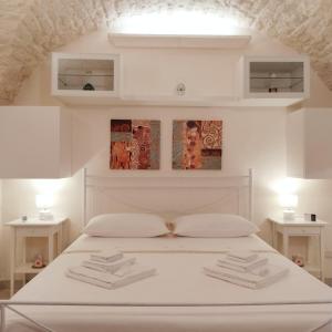 1 dormitorio con 1 cama blanca y 2 mesas blancas en L'Artefice, en Locorotondo