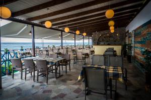 a restaurant with tables and chairs and the ocean at Stelakis Beach in Limenaria