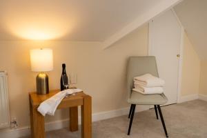 a chair and a table with a lamp and towels at The Limes in Harston