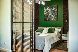 a bedroom with green walls and a bed with a window at Benefis Tatarska in Przemyśl