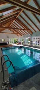 a large swimming pool with a chair in a building at Chambres d’hôtes plateau des mille étangs 