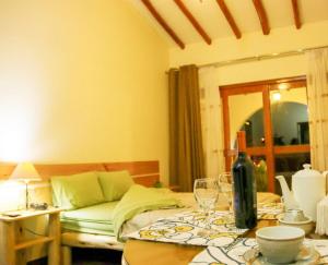 Habitación con cama y mesa con copas de vino en Fundo Alma Andina, en Jauja