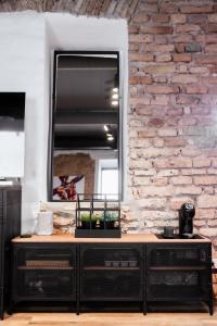 uma cómoda preta com um espelho numa parede de tijolos em BDSM Black Apartments em Vilnius