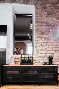 a black dresser with a mirror on a brick wall at BDSM Black Apartments in Vilnius