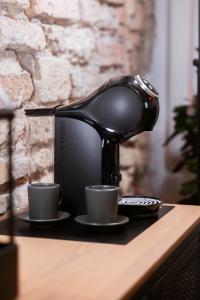 a coffee machine sitting on a table with two cups at BDSM Black Apartments in Vilnius