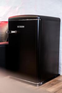 a black refrigerator sitting on top of a floor at BDSM Black Apartments in Vilnius +10 photos