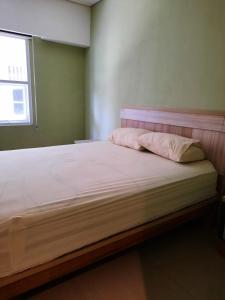 Cette chambre comprend un lit avec des draps blancs et une fenêtre. dans l'établissement OYO 93145 Pondok Alam Syariah, à Jakarta