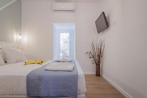 a white bedroom with a bed with a blue blanket at Little gem by the sea in Chania